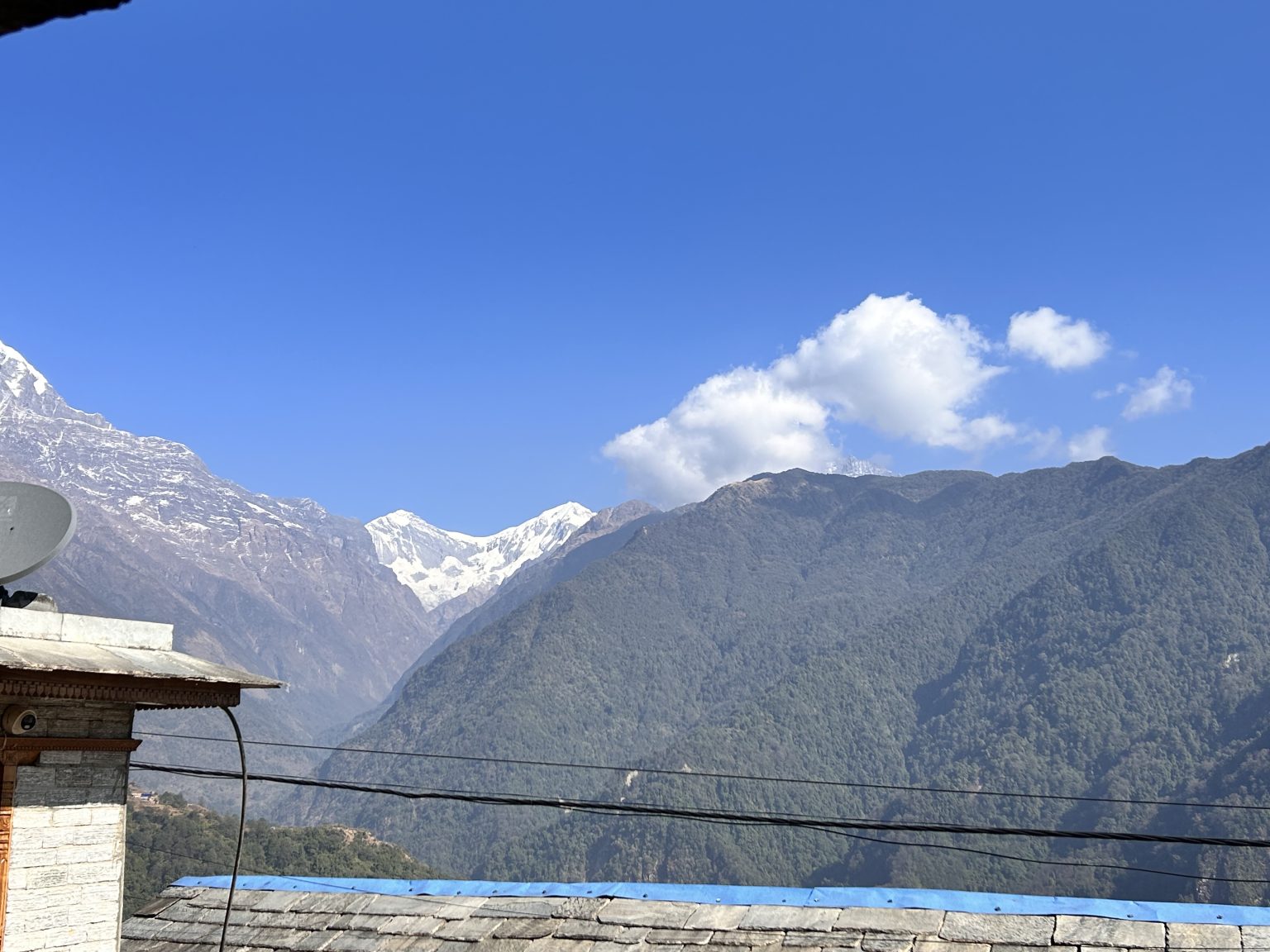 Scenic glimpse from a snug tourist homestay rooftop, featuring a TV satellite and snowy mountains in the backdrop!